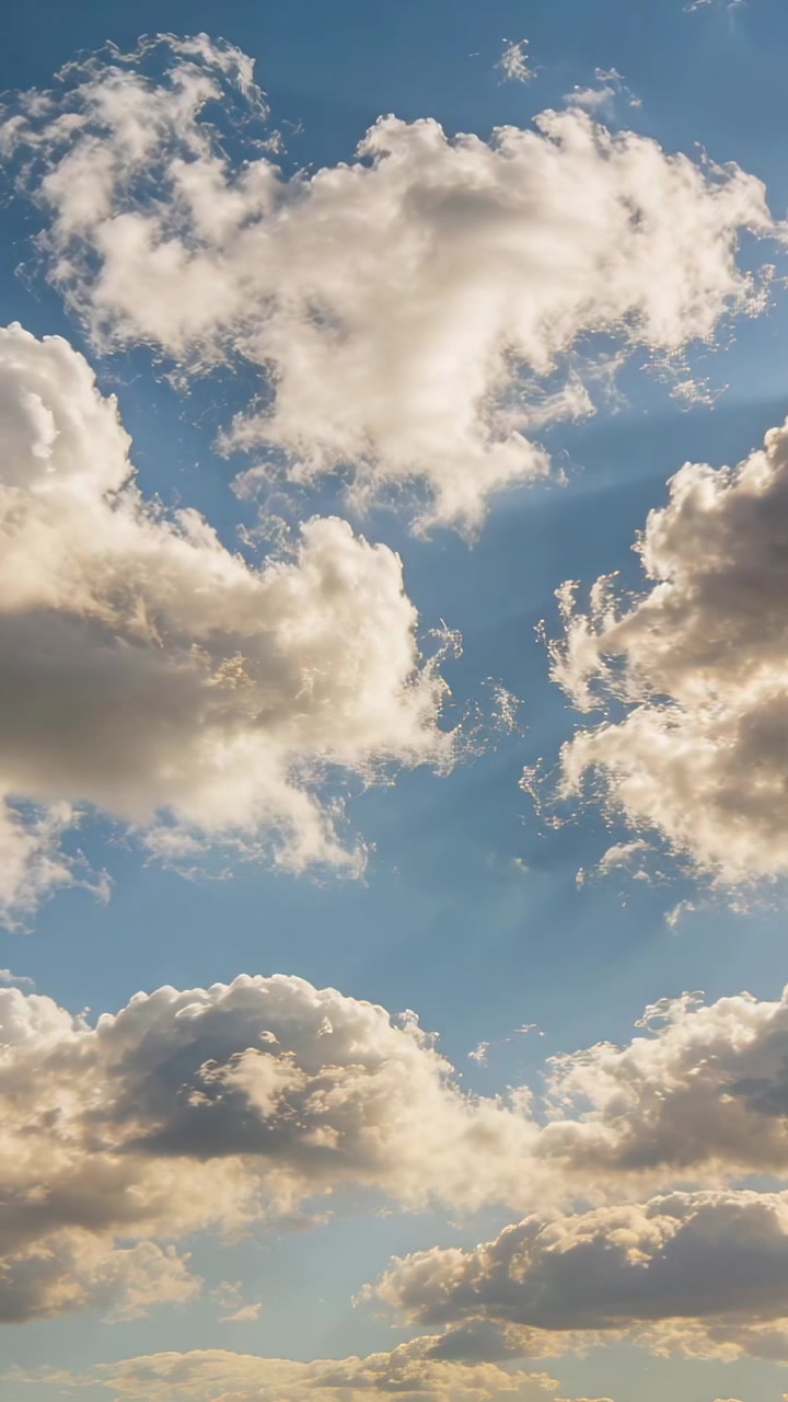 Video verticale: Vento leggero che muove una nuvola cumuliforme centrale nel cielo blu sopra banchi di nuvole più bassi, rilasciando filamenti.