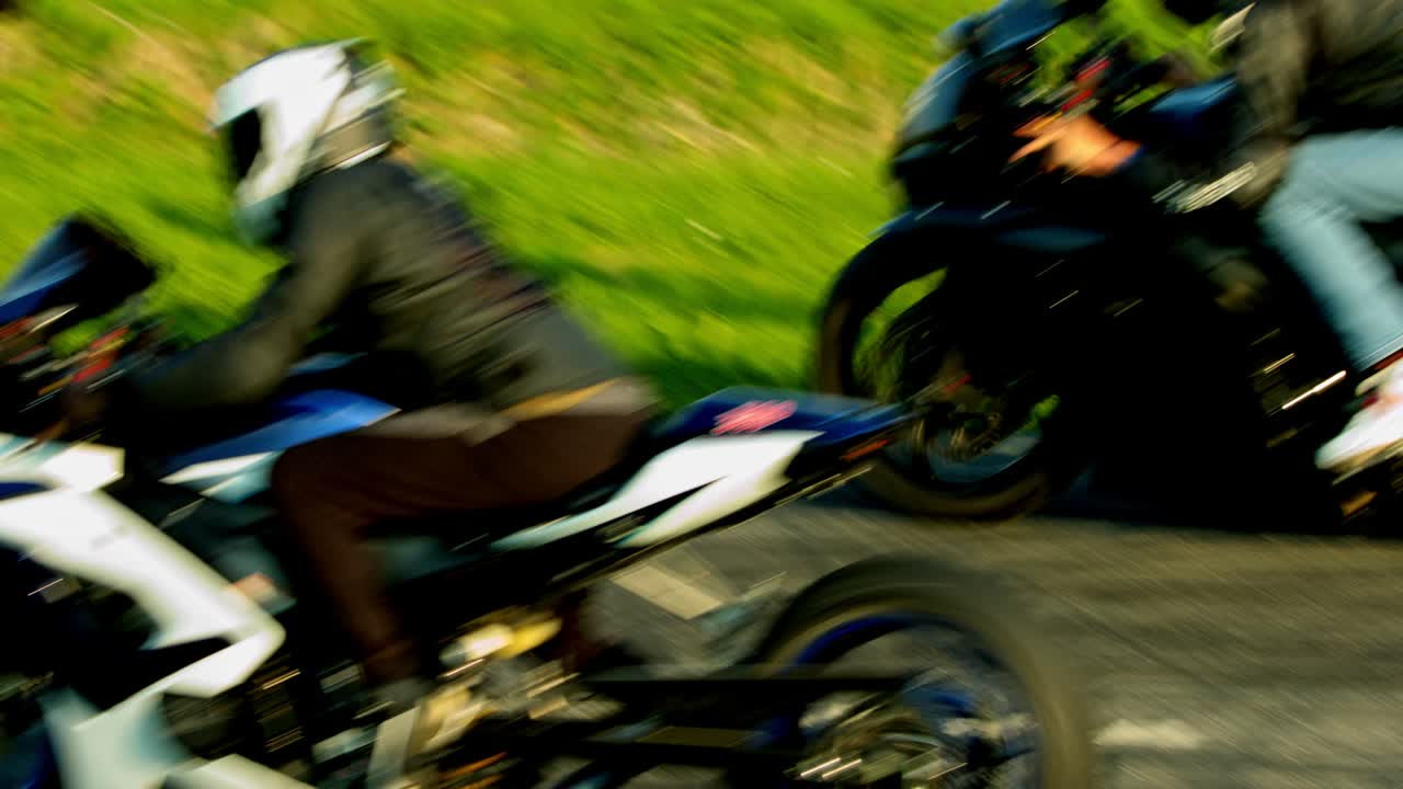 Two motorcyclists dressed up in complete racing attires racing over the tracks on sports bike. Slow motion.