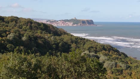 aerial drone footage of scarborough taken from a distance away over cayton bay with blue sky and ocean and big waves