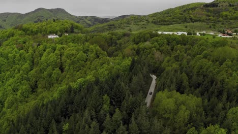 aerial drone flies over curved road into the autumn forest