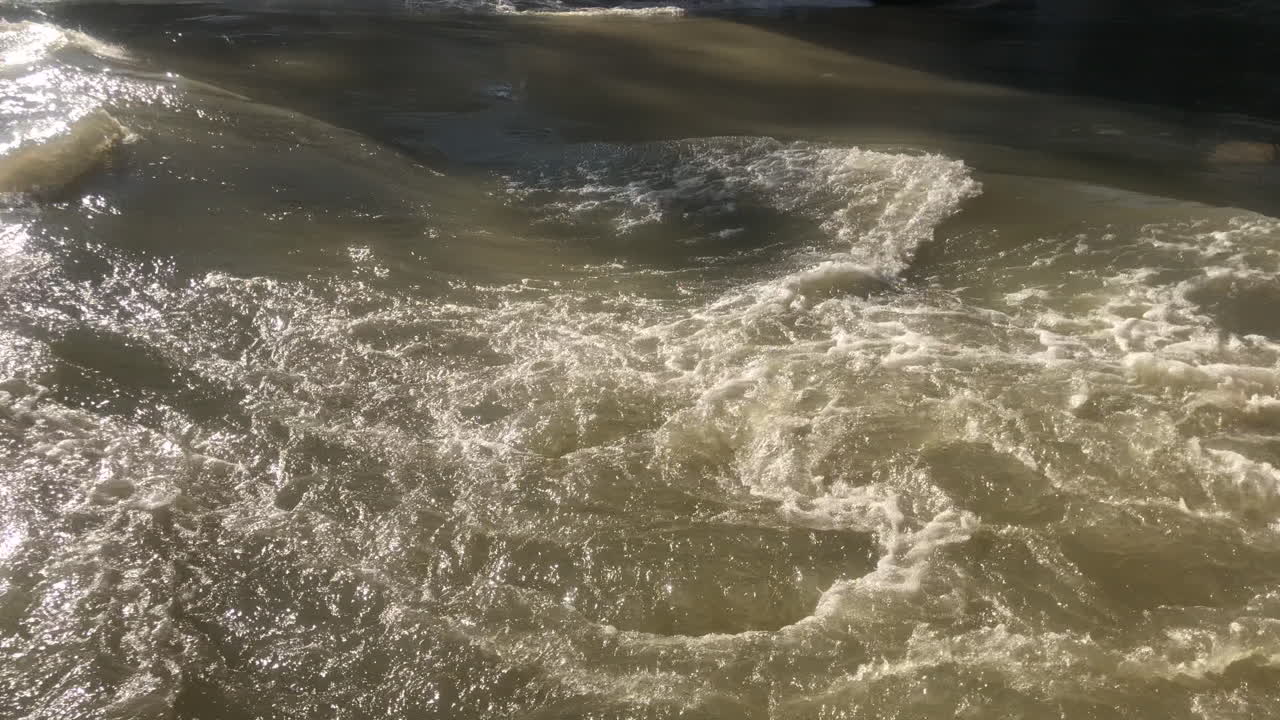 Slow moving tumultuous flow of water in a river on a sunny day