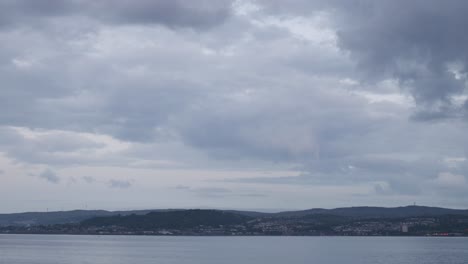 overcast sky over water and distant city landscape at dusk