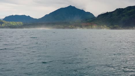 HD-120fps-Hawaii-Kauai-Boating-on-the-ocean-floating-right-to-left-with-mountain-and-hills-in-cloudy-distance-with-boat-spray-in-foreground,-slow-left-to-right-pan