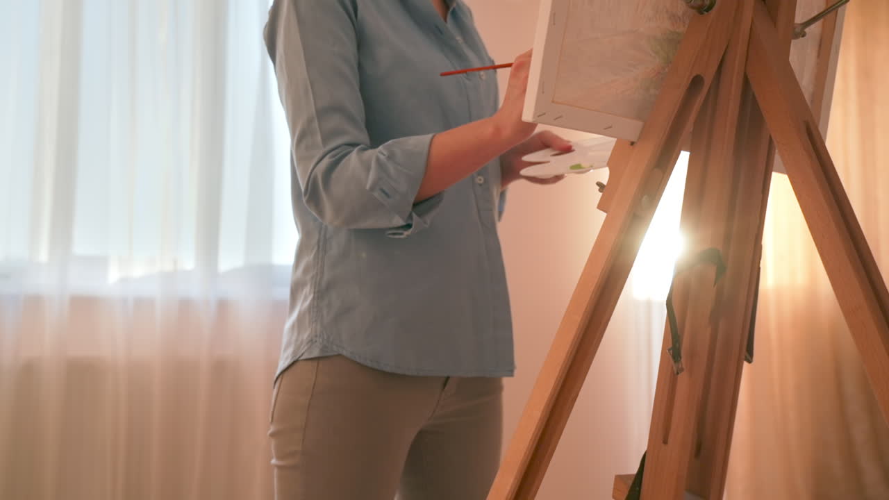 Caucasian woman painting a picture with a palette in her hands, indoors. Slow motion