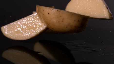 Potato-pieces-falling-on-wet-black-background