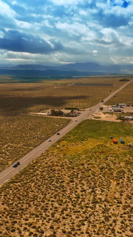 a few houses near the highway in nevada desert. rainy cloudscape covering the sky above the landscape. aerial view. vertical video
