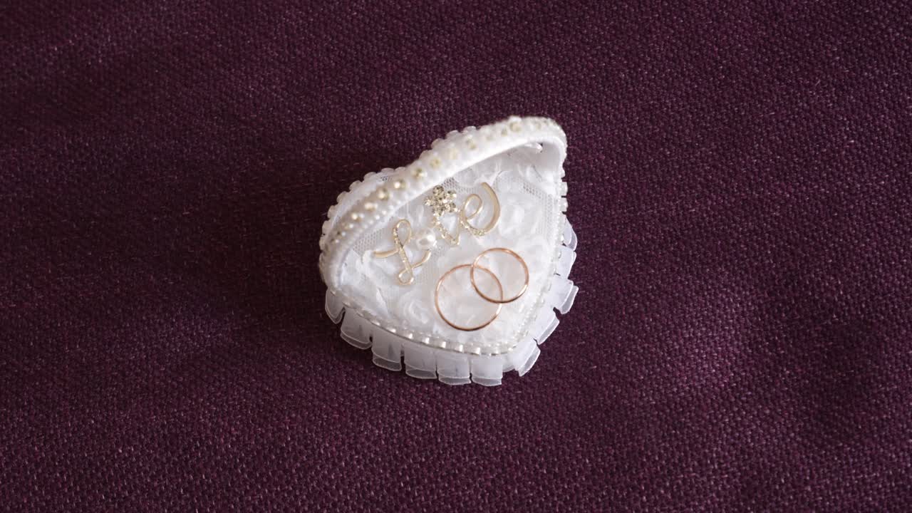 Два золотых обручальных кольца в элегантной белой коробке в форме сердца