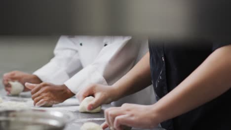 two diverse female chefs preparing dough and talking in restaurant kitchen