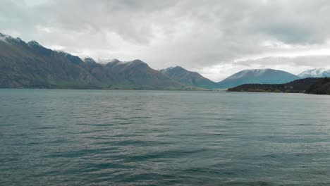 Slowmo---Flug-über-Den-Wunderschönen-Blauen-Lake-Wakatipu,-Queenstown,-Neuseeland-Mit-Bergen,-Neuschnee,-Wolken,-Blauen-Himmelsherbstbäumen-Im-Hintergrund---Luftdrohne