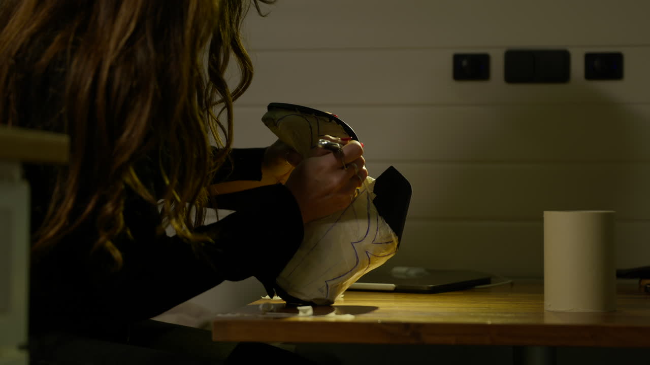 joven zapatero dibujando un diseño estampado en el cuero del zapato en el taller
