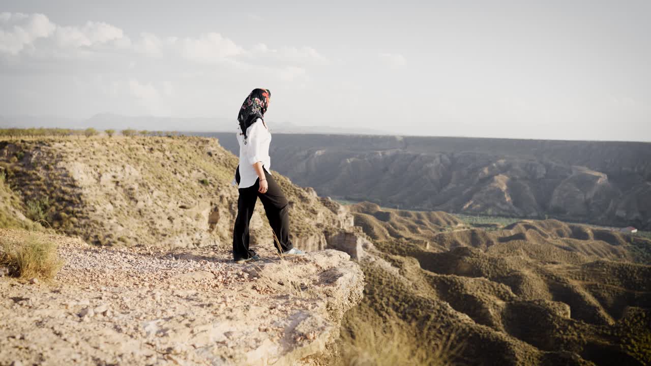 Adventurous woman walking to the edge of a canyon cliff