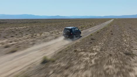 following a car off-roading in arid landscape near charyn canyon national park, kazakhstan