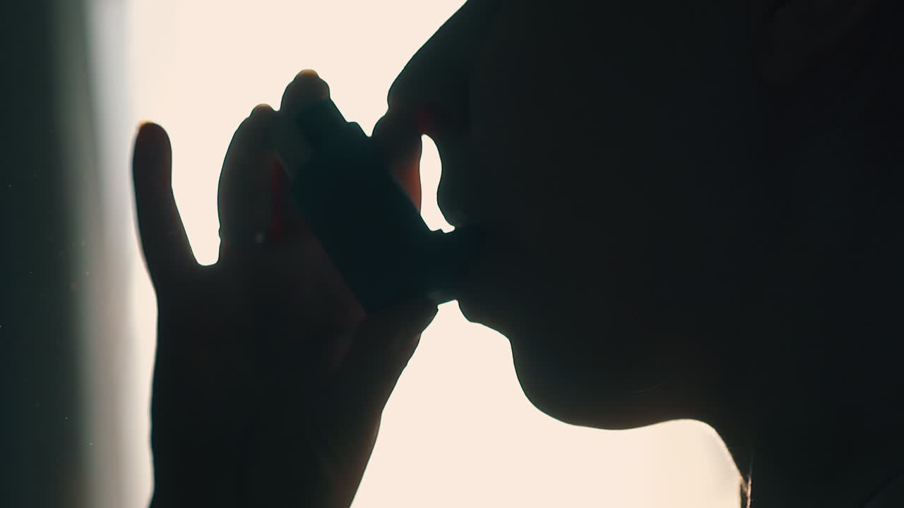 호흡을 위해 흡입기를 사용하는 사람의 실루