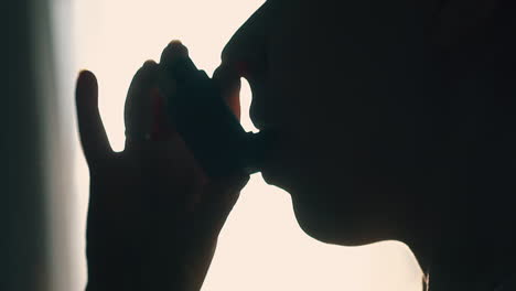 person-silhouette-using-inhaler-for-breathe-disease-closeup