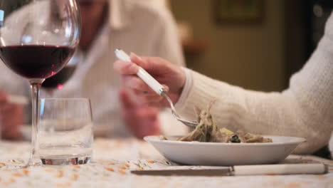 italian family dinner, close up, glass or red wine and plate with pasta. people sitting around table. selective focus, slow motion