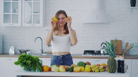 close-up of a thoughtful young woman cutting orange slices on a wooden table in a bright minimalist kitchen. she prepares fresh fruit for a healthy homemade smoothie