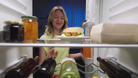 woman looking inside a refrigerator full of food