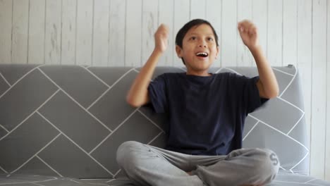 excited asian boy fans watching football with expression of joy