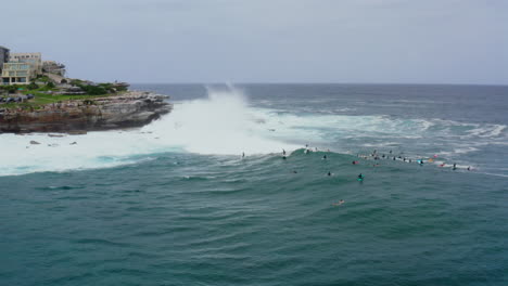 aerial: a crowd of surfers wait to catch the big swell at bondi beach, sydney australia