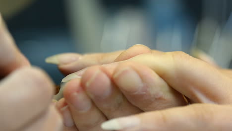 Closeup shot of a woman in a nail salon receiving manicure by beautician