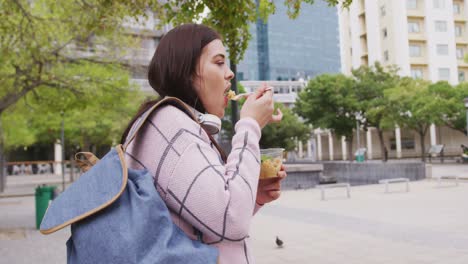 Young-Caucasian-woman-eating-and-walking