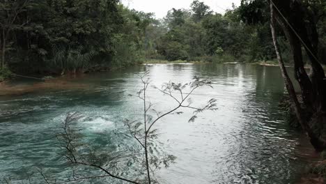 adventurous man swings on a rope swing and summersaults into a river in mexico