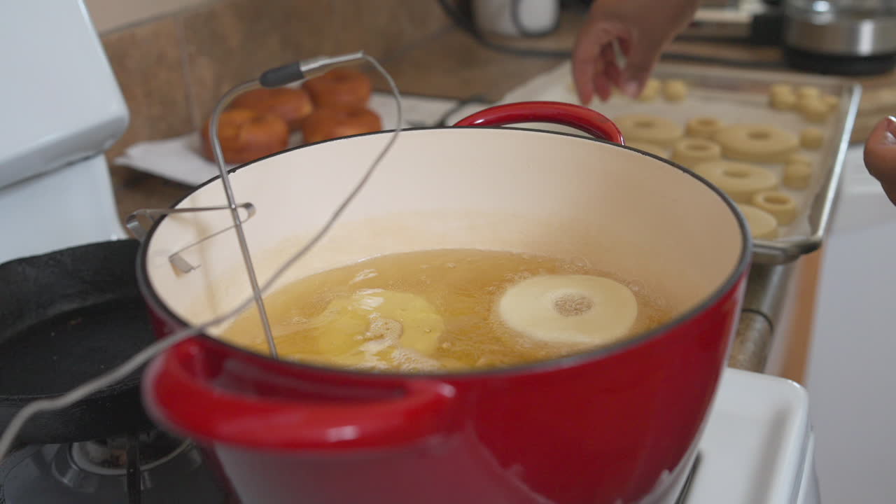 gotas de mano masa de donut en una olla con aceite de freír en la cocina de casa, cierre lento