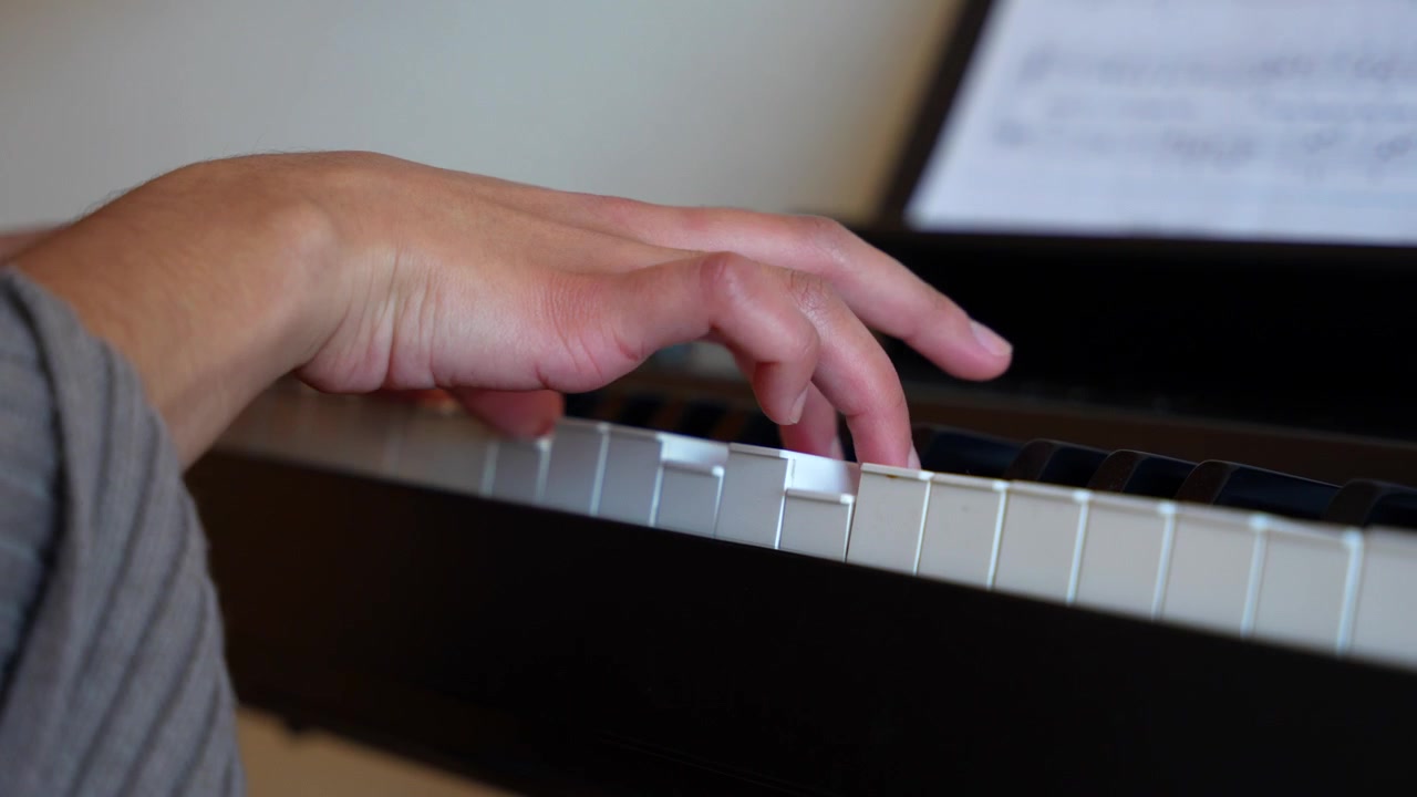 Detail of a female pianist playing a beautiful song on a classical piano at home