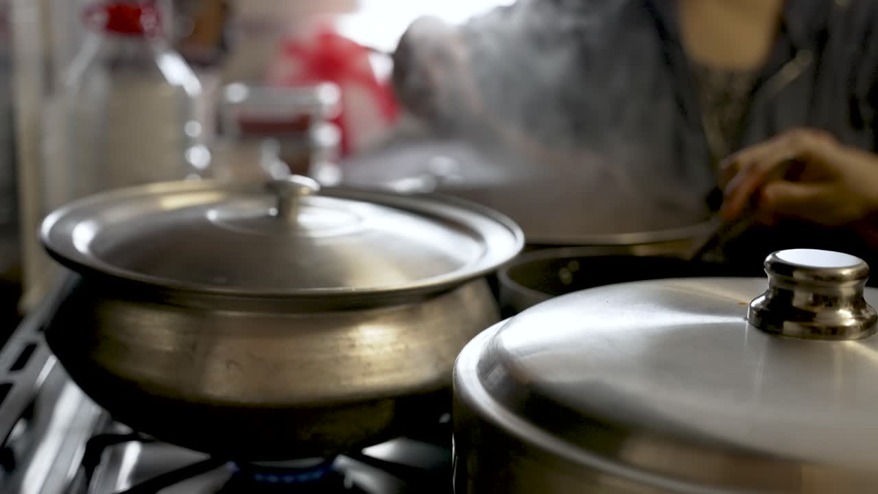 Cooking pots on a stove, individuals lifting lids and blending ingredients amid swirling vapor, embodying the essence of culinary artistry and gastronomy