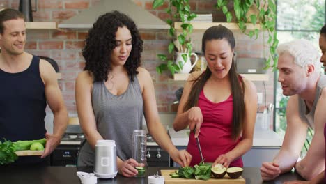 group of diverse young people making green healthy smoothie together at home