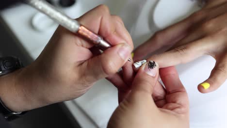 anonymous beautician applying lacquer on female client nails