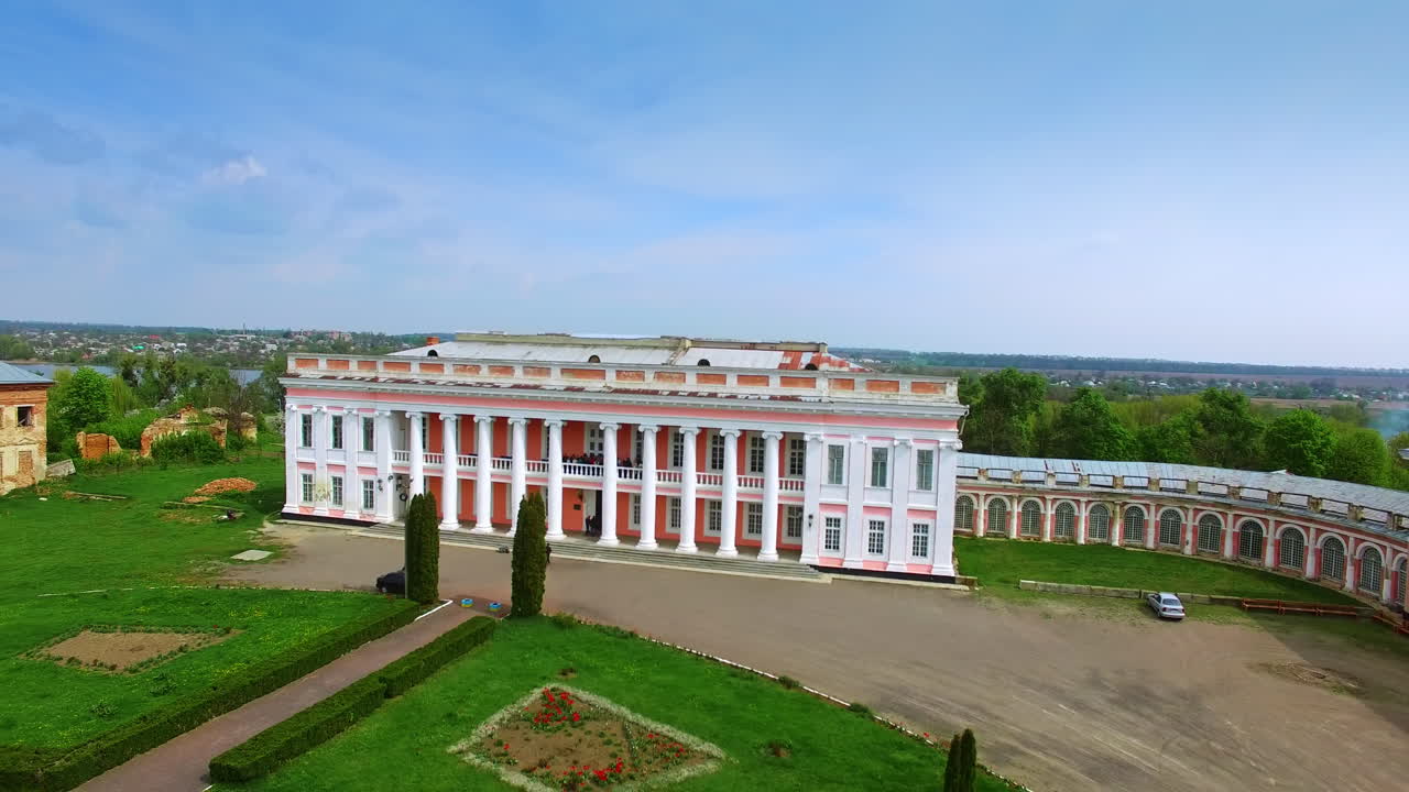 Distancing from a gorgeous two-storied palace with people on balcony. Neat territory in front of the building. Tulchin city, Ukraine.