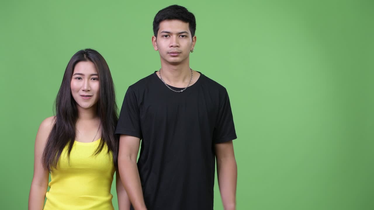 젊은 아시아 커플이 함께 무언가를 보여주고 있습니다.