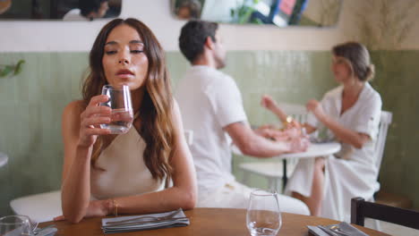 una mujer soltera bebiendo agua en una cafetería. una chica esperando a su novio. una cita fallida.