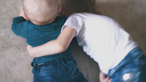 niños pequeños abrazados acostados en una cama grande y cómoda en casa