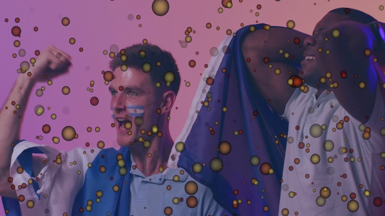 Two male soccer fans on pink gradient for sports, picking soccer ball and celebrating with confetti