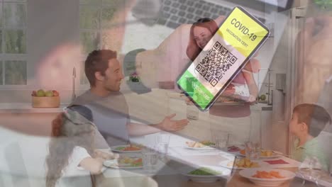 Hombre-Sosteniendo-Un-Teléfono-Inteligente-Con-Código-Qr-En-La-Pantalla-Contra-Una-Familia-Caucásica-Almorzando-Juntos