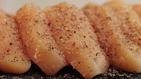 Raw slice chicken meat in spices: paprika, salt, pepper, turmeric on plate close-up. Preparing raw food for cooking. Grilled chicken, duck, turkey kebab with vegetables.