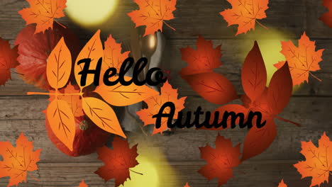 animation of hellow autumn text over cutlery and autumn leaves over wooden background