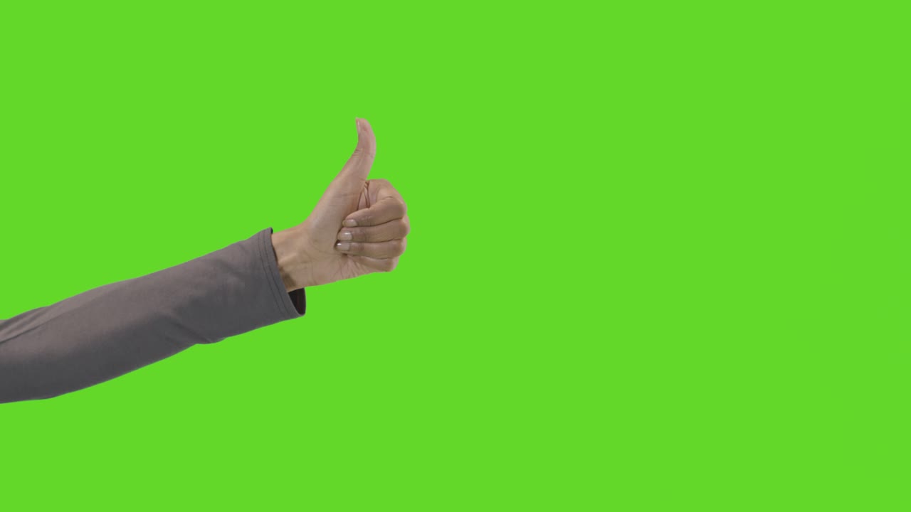 Studio Close Up Shot Of Woman Giving Thumbs Up Sign Against Green Screen