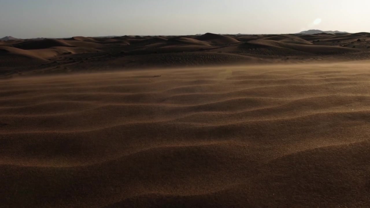 Tramonto nel deserto. Sabbia sollevata dal vento al rallentatore in un deserto. Paesaggio desertico mediorientale vicino a Dubai negli Emirati Arabi Uniti