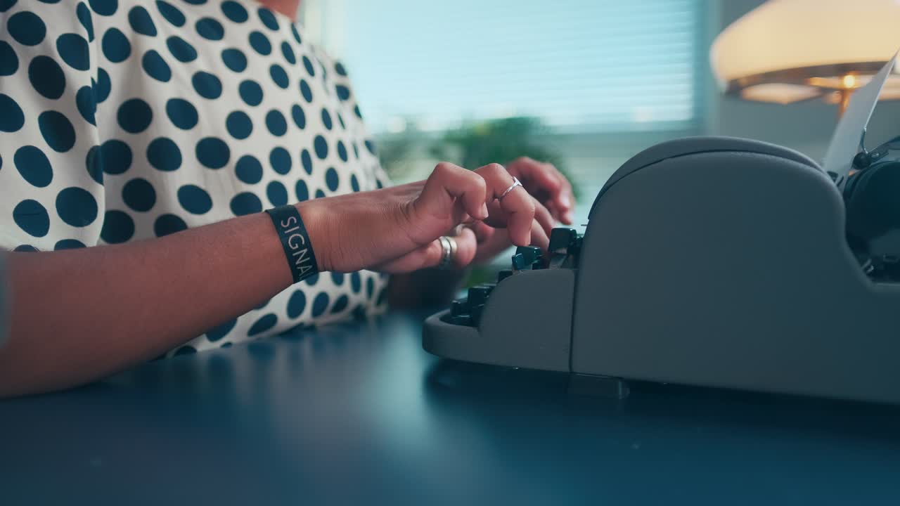 Young african american woman secretary typing on old typewriter sits in office