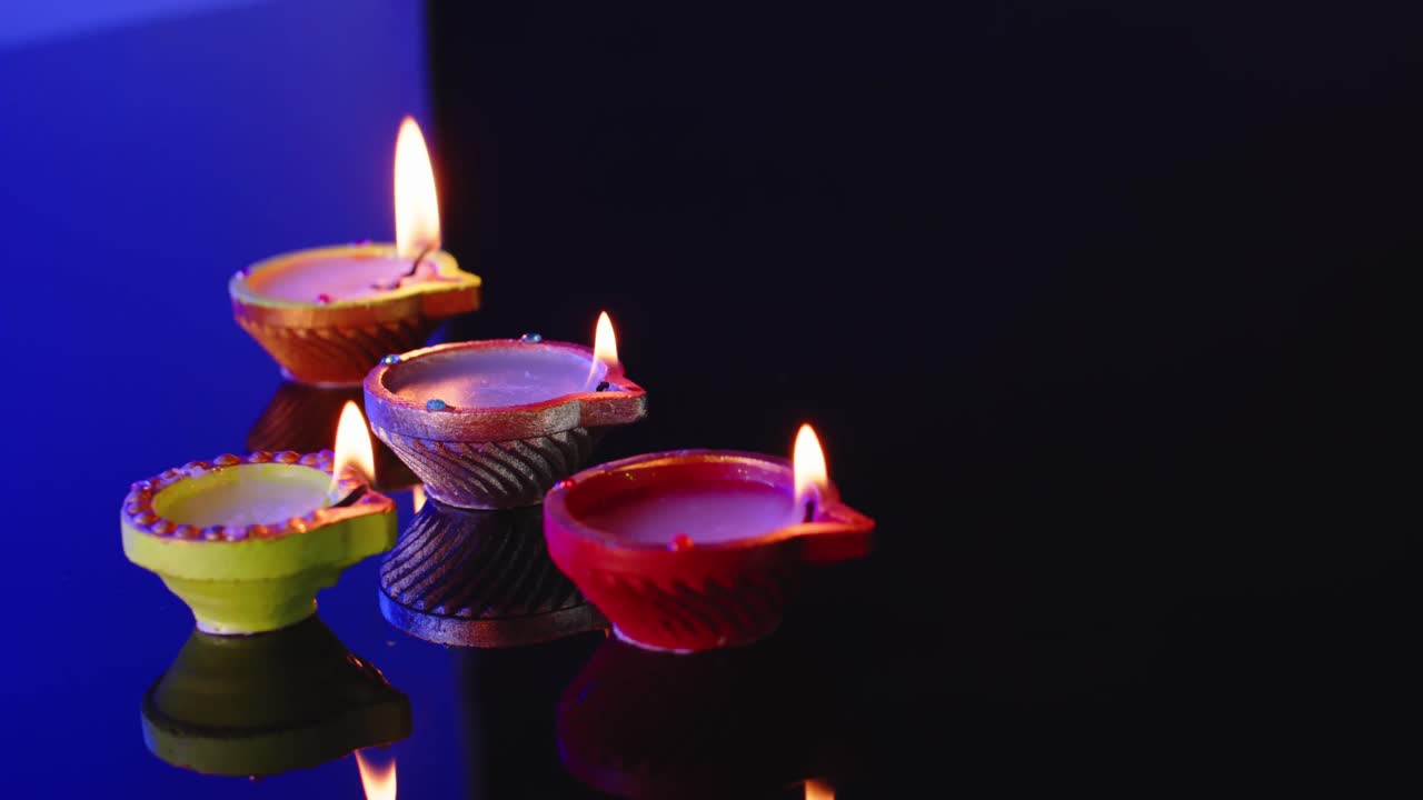 Primo piano di candele accese in fila che celebrano il Diwali su sfondo blu, con spazio per il testo