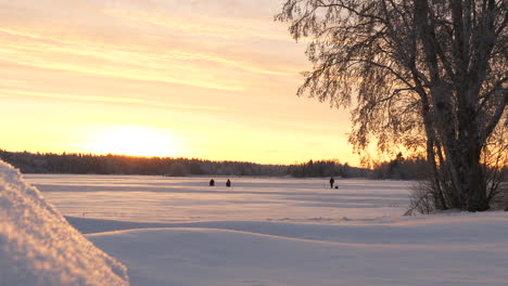 winter landscape covered with fresh powder and people in horizon during sunset, slow pan left