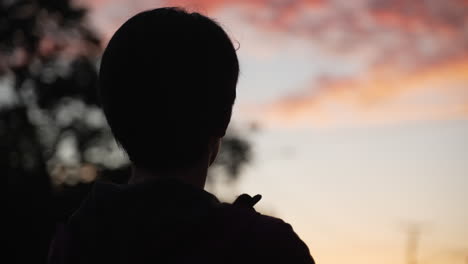 woman with short hair silhouetted against a golden hour cotton candy sky