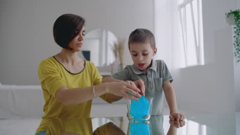 madre e hijo sentados en el suelo jugando en la mesa y riendo usando un juguete elástico.