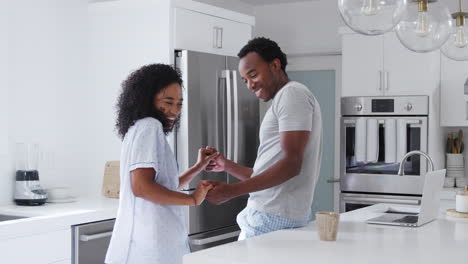 Loving-Couple-Wearing-Pyjamas-Having-Romantic-Dance-In-Kitchen-At-Home-Together