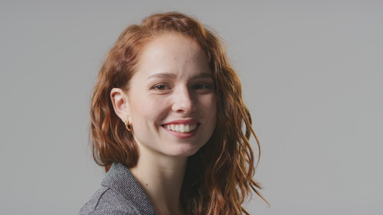 retrato de estudio de cabeza y hombros de una joven empresaria sonriente contra un fondo plano