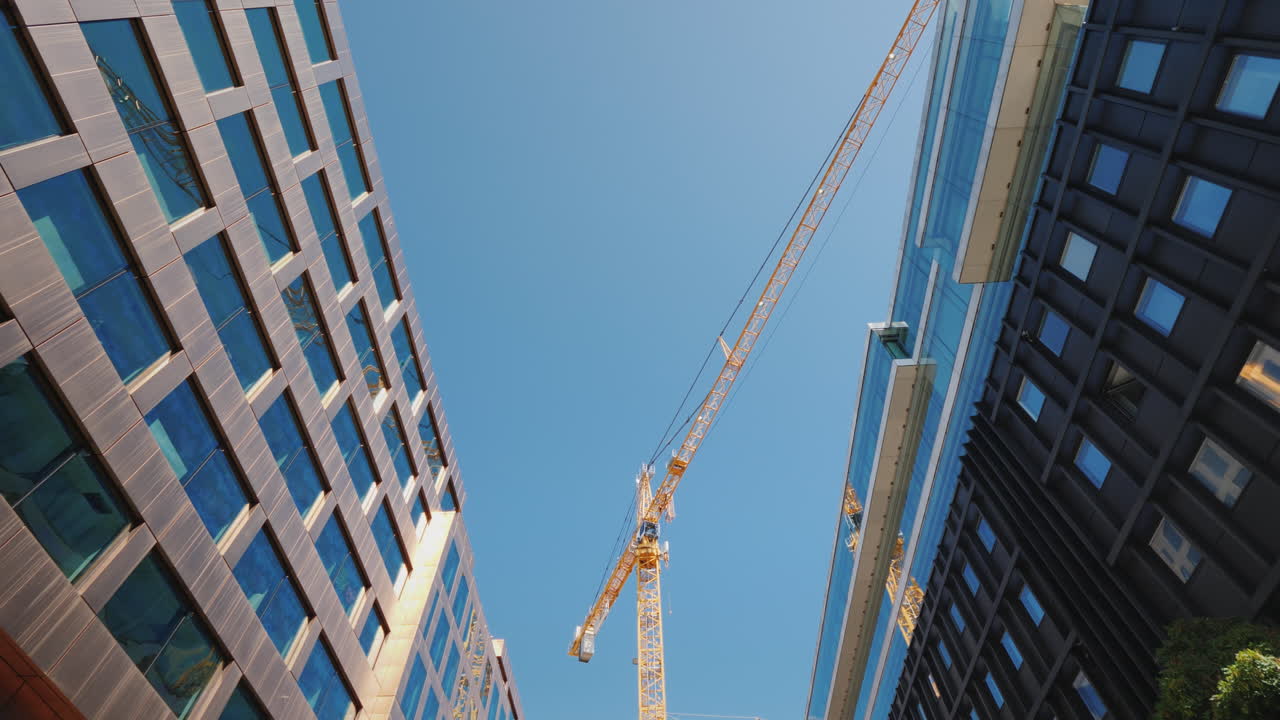 A Huge Construction Crane Near Office Buildings With Glass Facades City Building Steadicam Shot