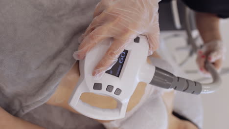doctor makes woman cavitation lpg vacuum roller massage on belly correction figures in spa clinic